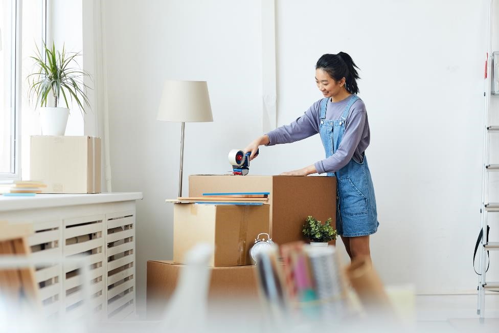 Person sorting belongings into labeled boxes: keep, donate, recycle, trash